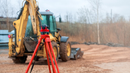 optical level on a rainy day against the background of standing tractor at a shallow depth of field