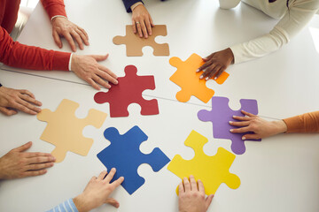 Business team looking for solution to problem. Diverse people join colorful puzzle parts as symbol of teamwork. Group of workers put colorful jigsaw pieces together as metaphor for creative search