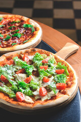 Caesar pizza served on a wooden table over blurred background in restaurant. Italian pizza with caesar salad filling.