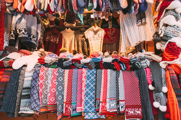Traditional Christmas Winter Market Trading Houses With Warm Clothes, Wear And Hats. Colorful Knitted Traditional European Warm Clothes - Mittens and Scarfs. Xmas Souvenir From Europe.
