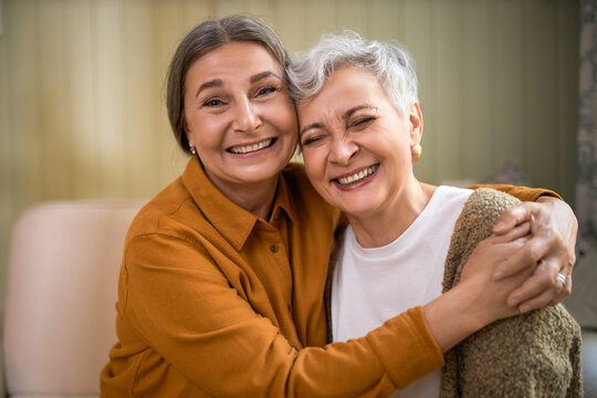 Joy, Fun And Happiness. Indoor Shot Of Happy Senior Female In Shirt Hugging Her Short Haired Female Friend Laughing At Joke, Enjoying Nice Time Together. Two Middle Aged Best Friends Relaxing