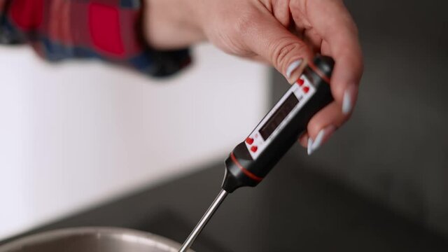 Thermometer measures the temperature in a saucepan with syrup