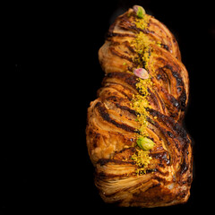 Pastry with chocolate and pistachio on black background
