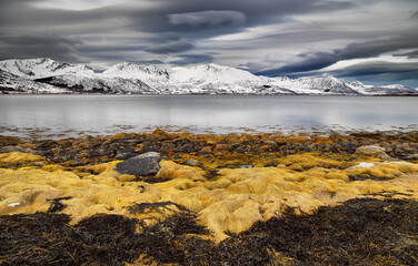 Long exposure image of a landscape with snow covered mountains and a fjord on the Vesteralen islands in northern Norway