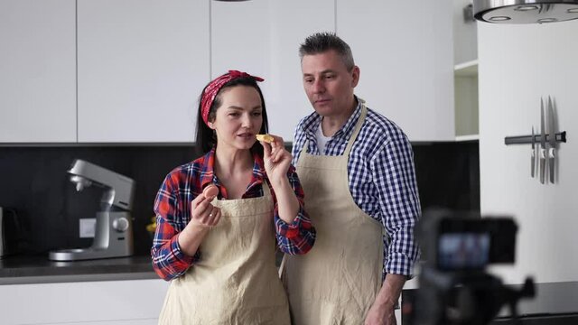 Positive couple at kitchen baking at home, talking on camera