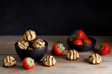 Homemade coconut biscuits with strawberry. Homemade vegan coconut cookies dipped in chocolate. Served in bowl with strawberry's on the side.