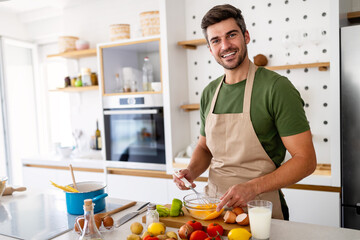 Happy caucasian man cooking in kitchen at home, smiling.