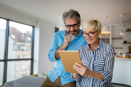 Happy smiling mature couple using digital tablet at home