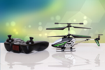 Closeup of a little RC toy helicopter and a remote controller on a bright table against abstract futuristic yellow blue background. Macro photograph.