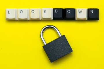 a closed padlock with keys on a yellow background at the top the inscription lockdown is laid out from the keys of a computer keyboard the concept of data protection prohibitions