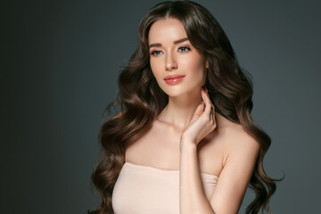 Beautiful woman with long hair, shine and curly, beauty girl female over darl gray background