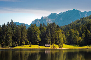 Alpine lake shore with old wooden barn