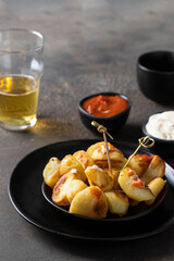 Patatas bravas o brave potatoes image. Famous Spanish tapa, fried potatoes served with beer,  spicy tomato sauce and aioli on concrete table.