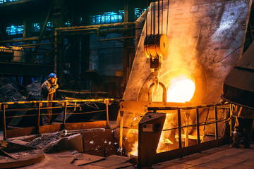 Molten iron pouring from blast furnace into ladle container, steel foundry factory, heavy metallurgy industry.