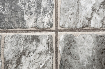 Monochrome rough tiles granite or marble polishes with seams between them close-up