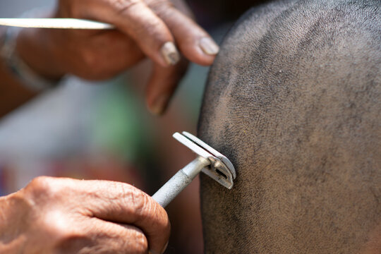 Close-up image of people are using a razor blade to shave their hair for a person to be ordained in the Buddhist Ordination, a traditional Buddhist culture.