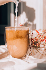 Milk pouring into the glass cup with black coffee. Morning aesthetics vibes. Breakfast. Pink...