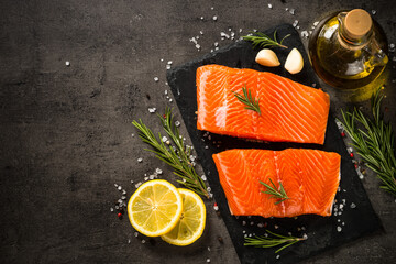 Salmon fish with ingredients at black table.