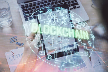 Double exposure of man's hands holding and using a phone and crypto currency blockchain theme drawing.