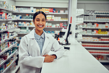 Portrait of smiling happy confident young woman pharmacist leaning on a desk in the pharmacy - 431456165