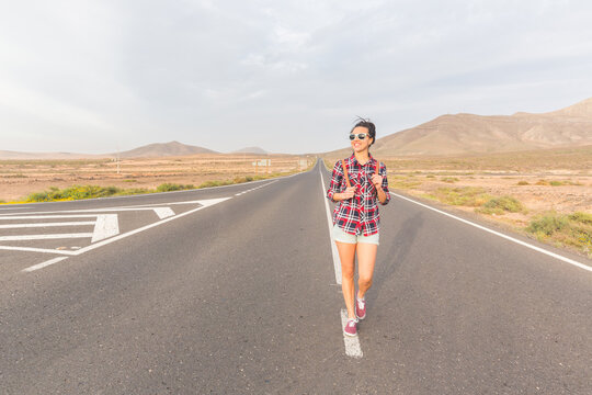 Happy woman walking on empty road in Fuerteventura
