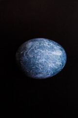 Easter egg painted in the form of a planet in space in blue on a black background. Marble dyed for Easter painted in hibiscus