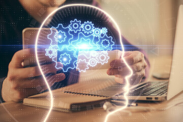 Double exposure of man's hand holding and using a digital device and brain hologram drawing. Data concept.