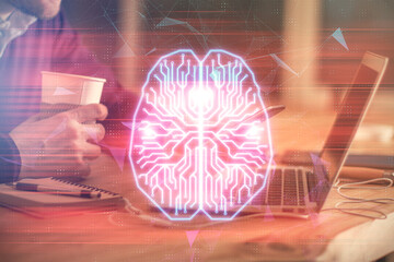 Double exposure of man's hand holding and using a digital device and brain hologram drawing. Data...