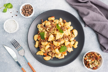 Stewed pasta with minced beef and vegetables, macaroni in Navy style on a plate. grey concrete background.