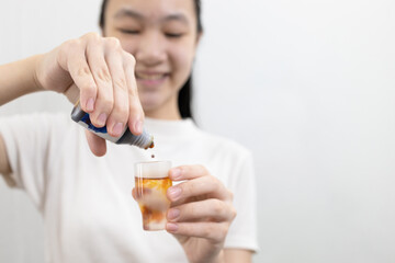 Girl holding a bottle of medicine for rinsing the mouth or gargling,dripping an antiseptic into a...