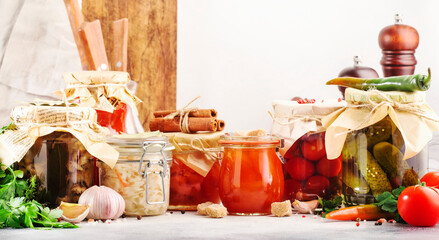 Fermented, pickled, marinated preserved vegetarian food. Summer organic vegetables and fruits in jars with spice and herbs on white kitchen