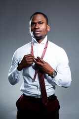 Serious handsome african american businessman going to work tying tie around his neck
