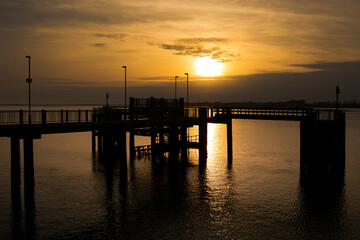 Fototapeta na wymiar Caernarfon pier, on Victoria Dock, reflected in sea at sunset. Holiday resort destination in Wales