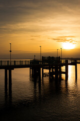Fototapeta na wymiar Caernarfon pier, on Victoria Dock, reflected in sea at sunset. Holiday resort destination in Wales