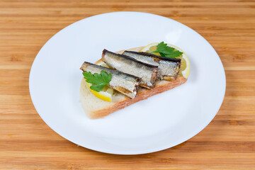 Open sandwich with preserved smoked sprats and lemon slices