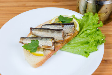Open sandwich with preserved smoked sprats and lemon close-up