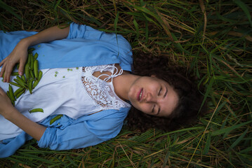 Girl with green peas in the grass