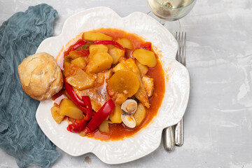 portuguese fish stew with bread in white dish and glass of wine