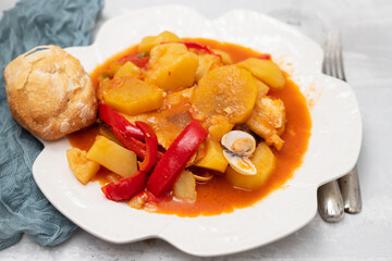 portuguese fish stew with bread in white dish and glass of wine