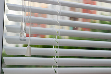 Fragment of white horizontal blinds with manual control, close-up