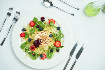 Grilled camembert cheese with apples, strawberries and blueberries in a white plate on a white plate. Close up, selective focus