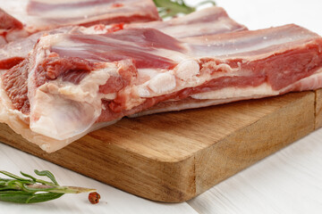 Raw meat ribs on wooden board on white background