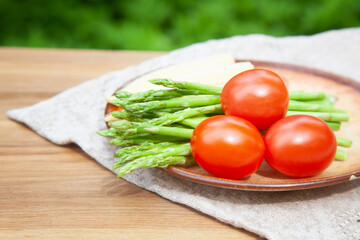 Fresh red tomatoes and green asparagus on a plate, summer vitamins and healthy food concept