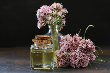 Essential oil in bottle with blooming valerian plant