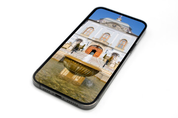 Isolated smartphone on white background, sharp display with fountain and castle on the background