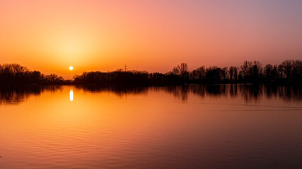 Beautiful sunset with reflections on a day with lots of sahara dust in the air near Plattling,...
