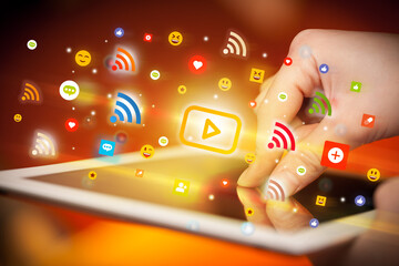 Close-up of a hand using tablet with social media icons