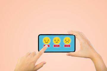 Customer Feedback Concept : Hand choosing yellow smile emotional icons for giving best service ranking on smartphone.