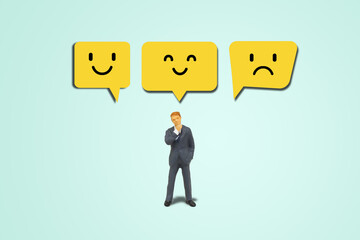 Customer Feedback Concept : Businessman standing and thinking to choose face emotional icon symbols.