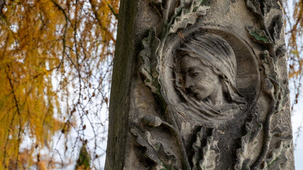 Płaskorzeźba przedstawiająca głowę, twarz kobiety otoczona roślinnymi motywami.